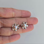 Pair of pearl earrings held between two fingers on a plain background