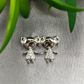 A sterling silver pendant featuring two girl figures with cubic zirconia accents, displayed against a textured background.