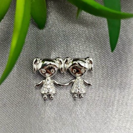 A sterling silver pendant featuring two girl figures with cubic zirconia accents, displayed against a textured background.