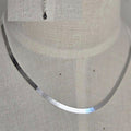 Silver necklace on a mannequin with a close-up inset of the pendant.
