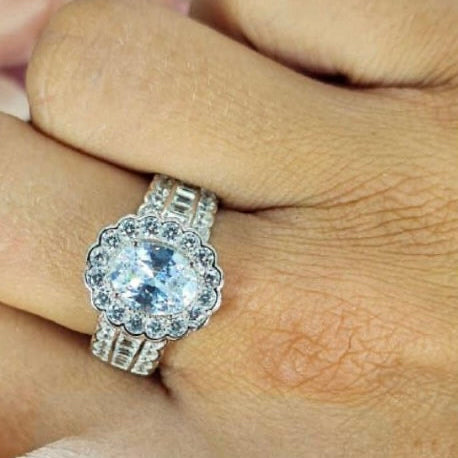 A sterling silver ring with an oval cubic zirconia centerpiece, displayed on a person's finger.
