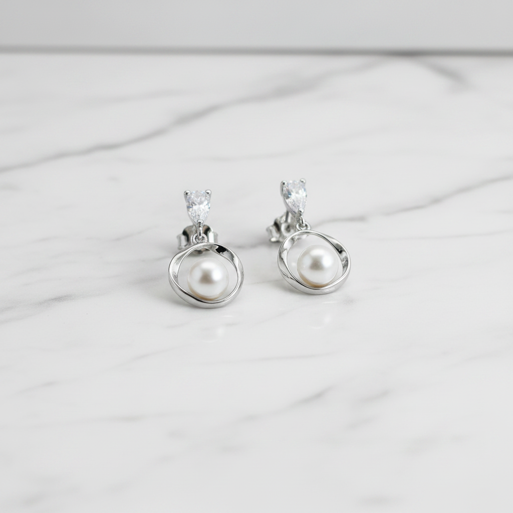 A pair of sterling silver drop earrings with cubic zirconia stud tops, displayed in a white vase with a green plant in the background.