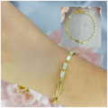 A gold-plated sterling silver bracelet with cubic zirconia embellishments, displayed on a wrist against a floral background.