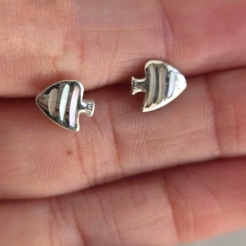Silver fish-shaped earrings on a hand