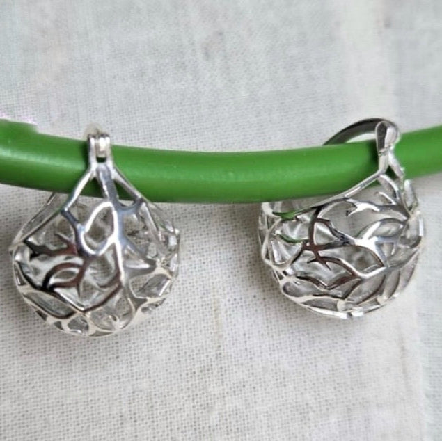 Silver earrings on a green stick against a light fabric background