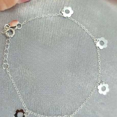 A sterling silver bracelet featuring a series of daisy-shaped charms linked together.