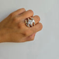 A hand wearing a sterling silver ring with three bands and diamond-shaped cubic zirconia in the center.