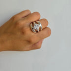 A hand wearing a sterling silver ring with three bands and diamond-shaped cubic zirconia in the center.