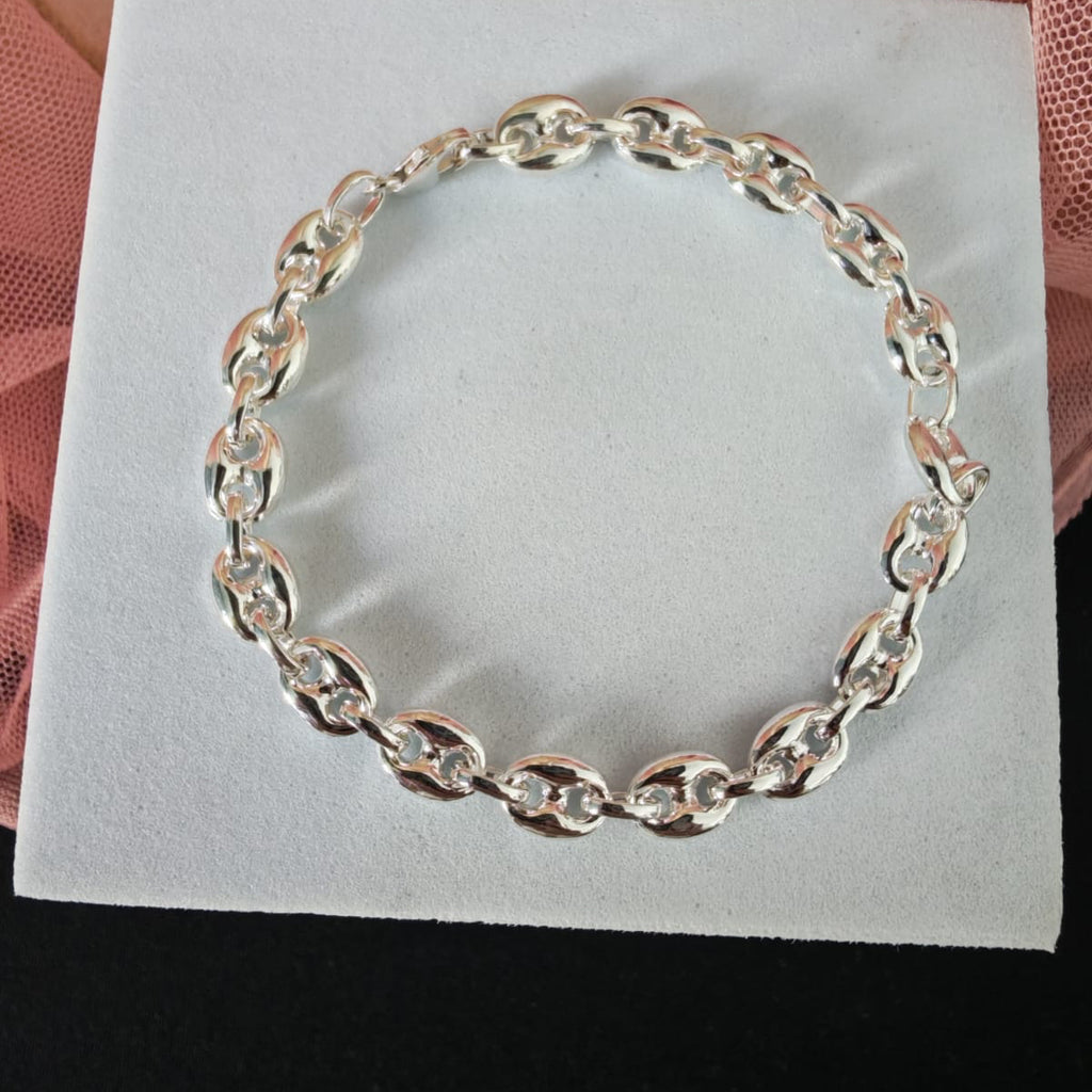 Silver bracelet on a white card with a pink fabric background