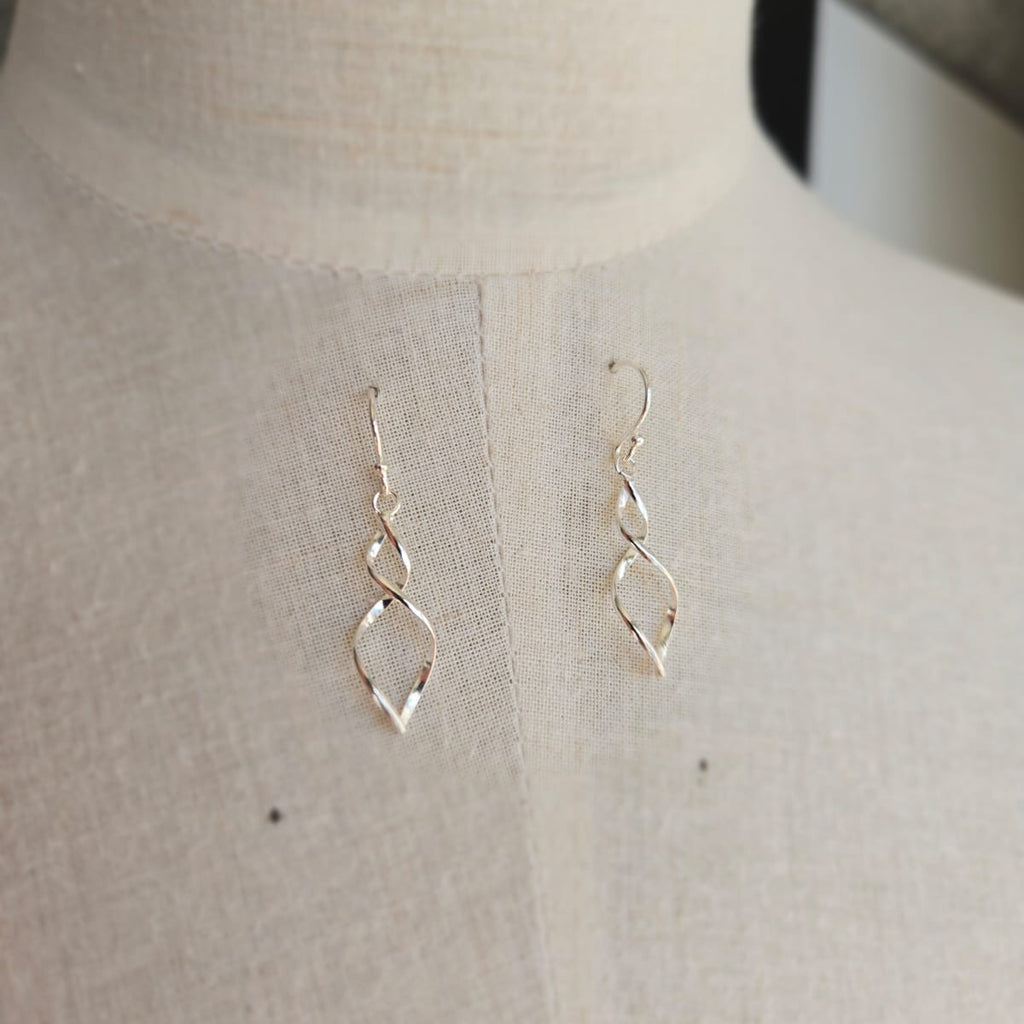 Gold earrings on a mannequin bust against a neutral background
