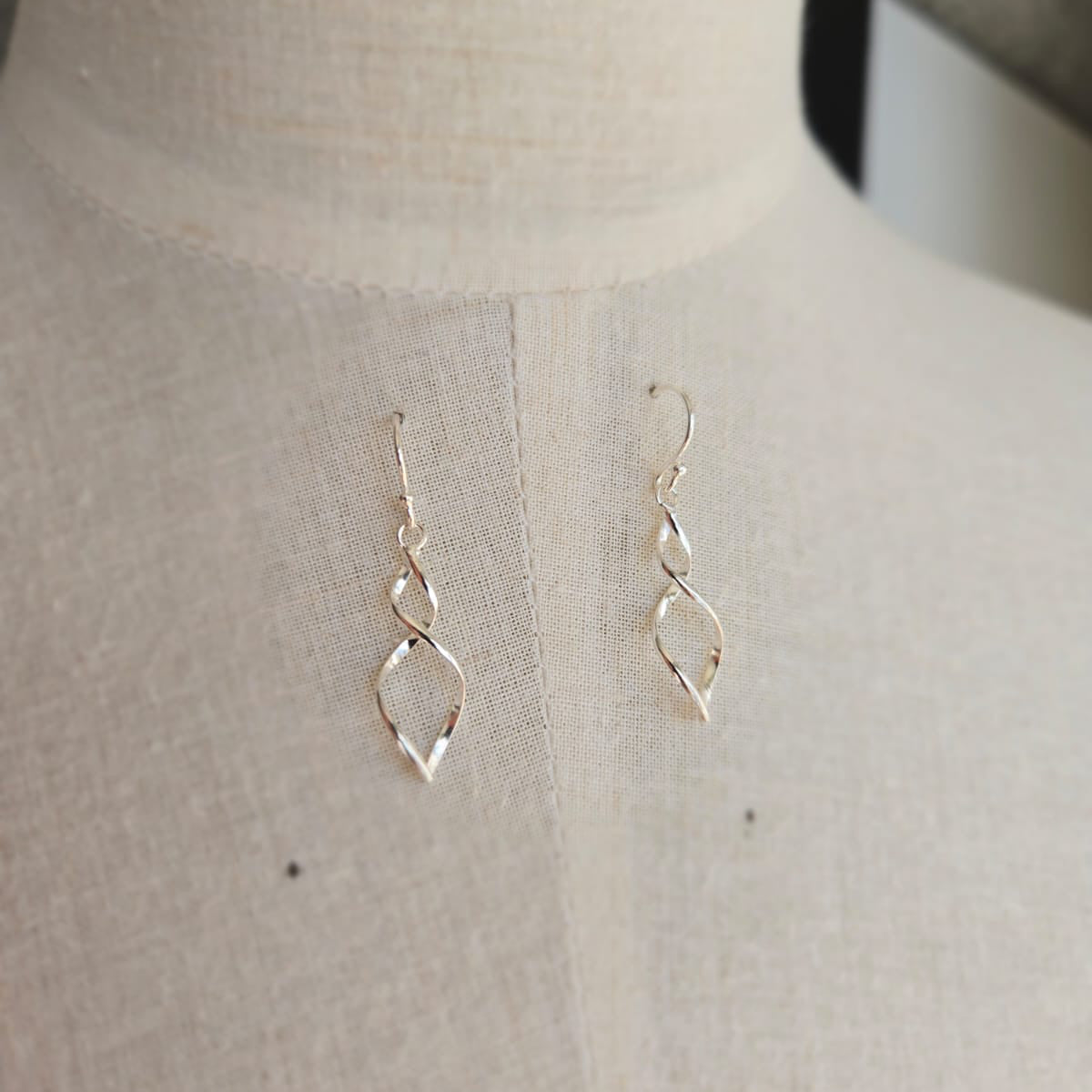 Gold earrings on a mannequin bust against a neutral background