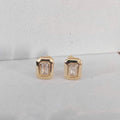 Gold earrings with gemstones on a light gray background