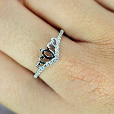 An elegant sterling silver ring with a crown design set with cubic zirconia, displayed on a person's finger.