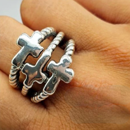 A sterling silver ring with three cross symbols stacked on top of each other, displayed on a person's hand.
