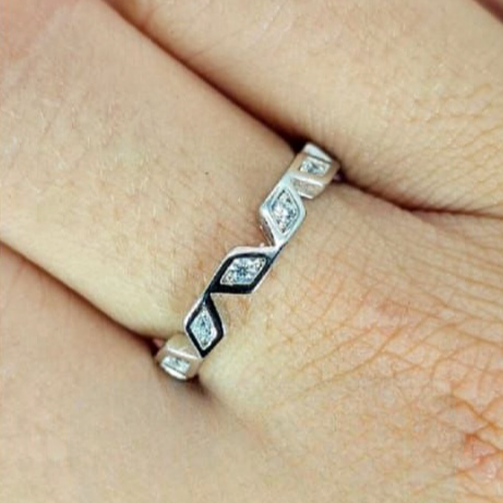 A sterling silver eternity ring with cubic zirconia inserts on a person's finger.