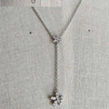 Silver necklace with floral pendants on a textured gray background