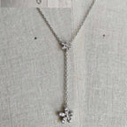 Silver necklace with floral pendants on a textured gray background