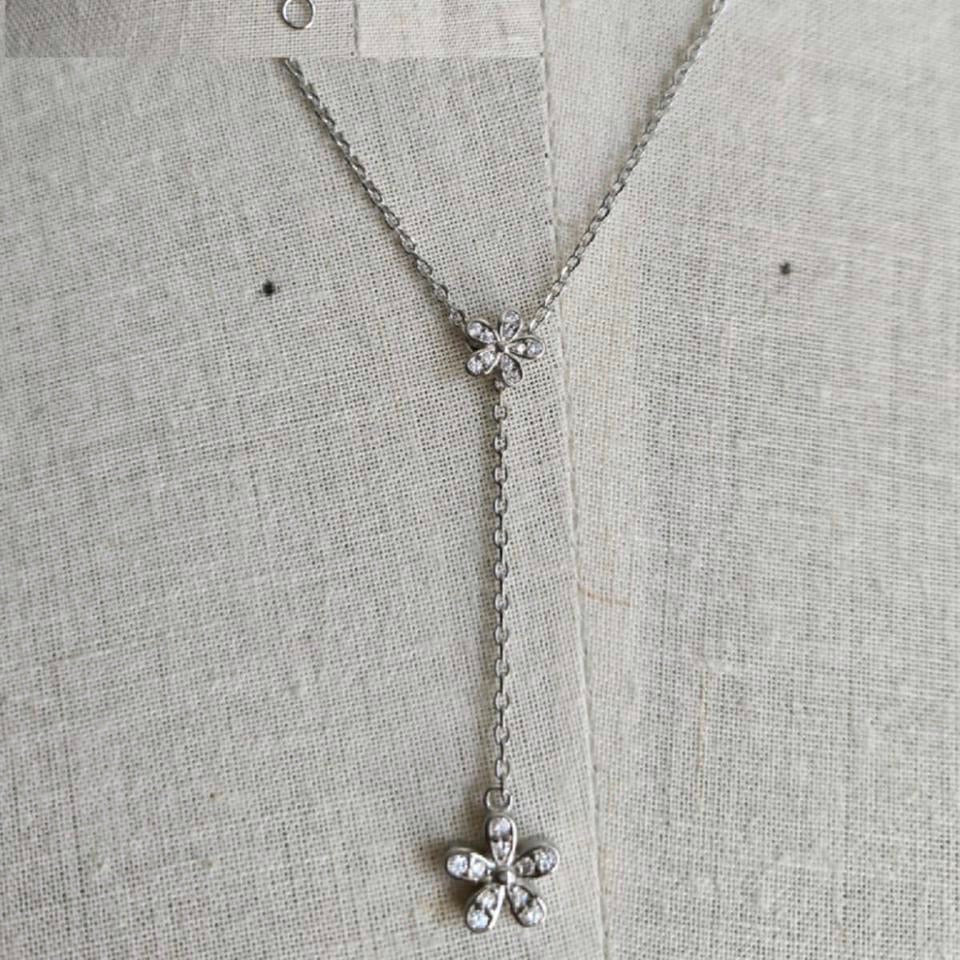 Silver necklace with floral pendants on a textured gray background