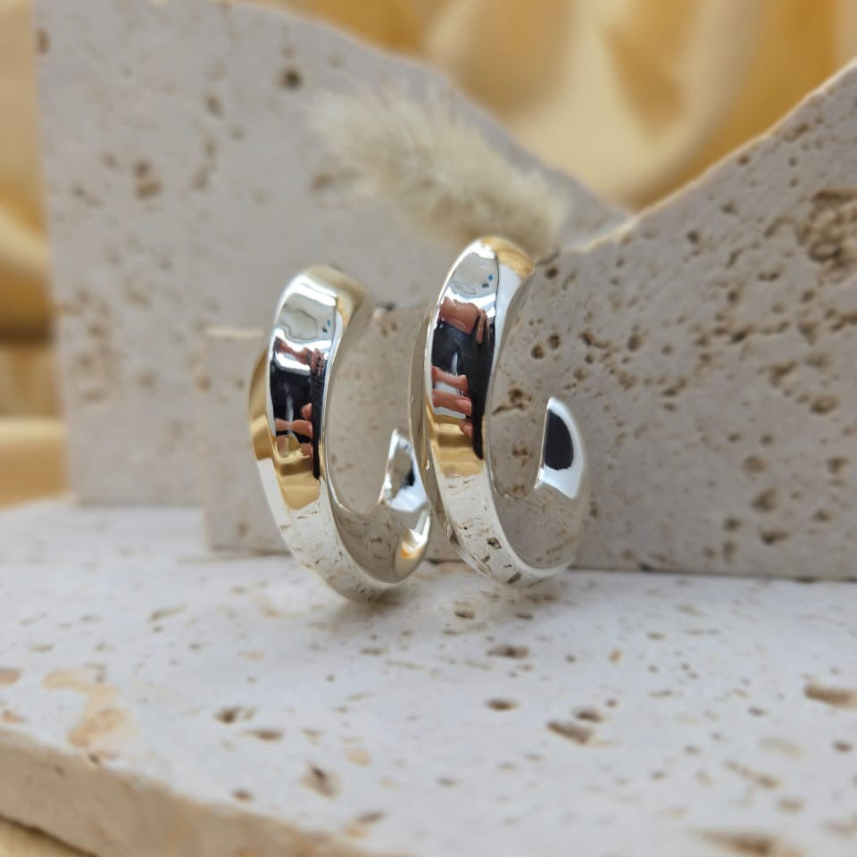 Two silver rings on a textured stone surface with a blurred yellow background