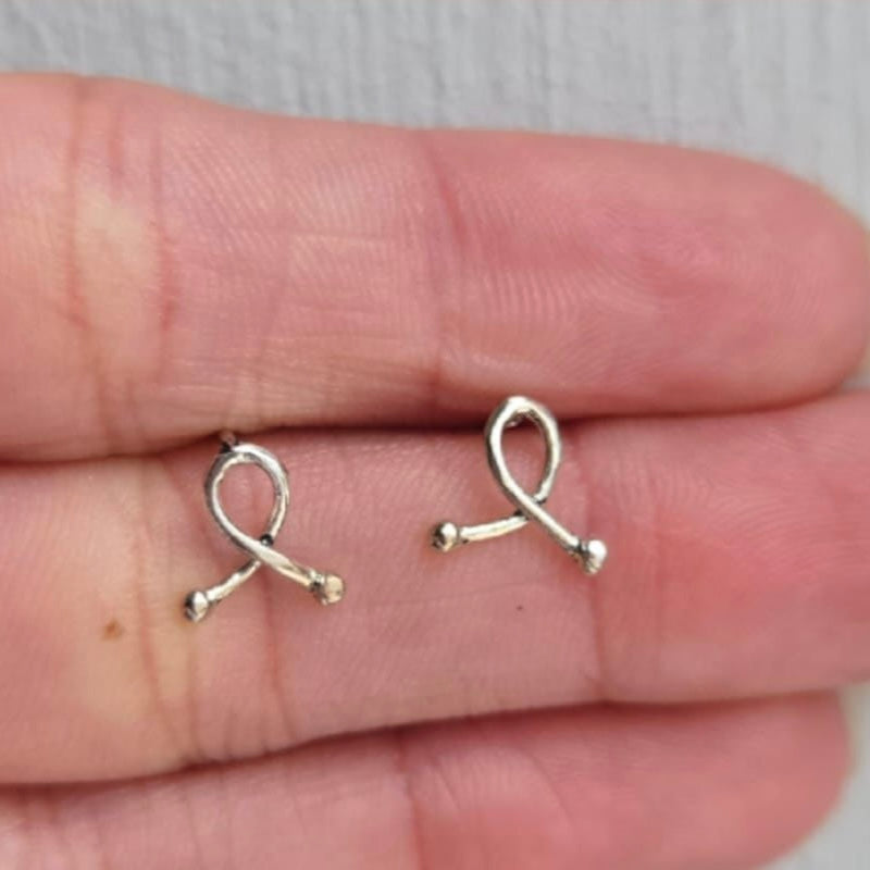 Silver ribbon-shaped earrings on a person's hand