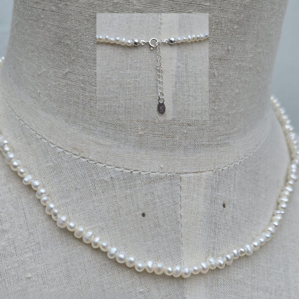 Pearl necklace on a mannequin with a gray background