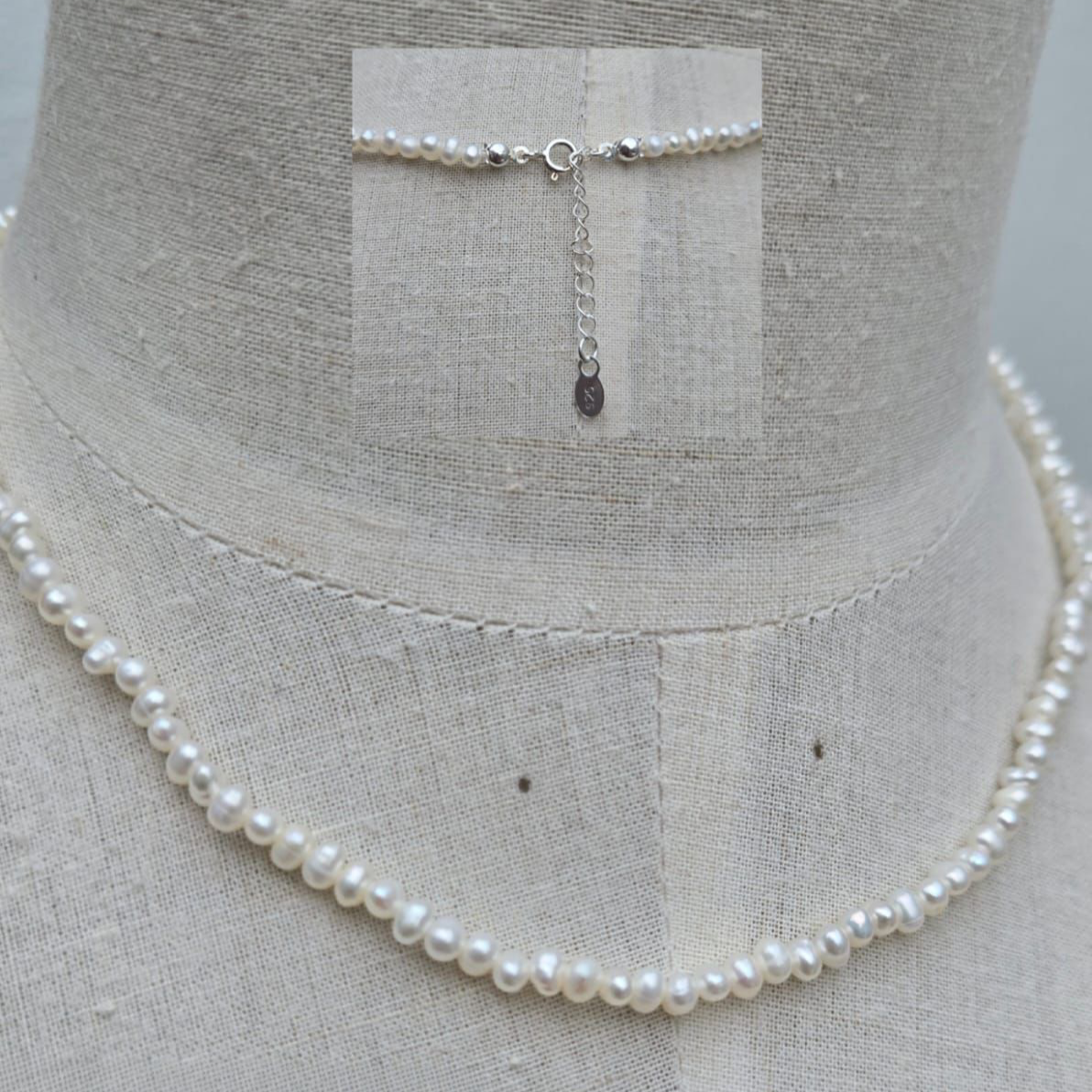 Pearl necklace on a mannequin with a gray background