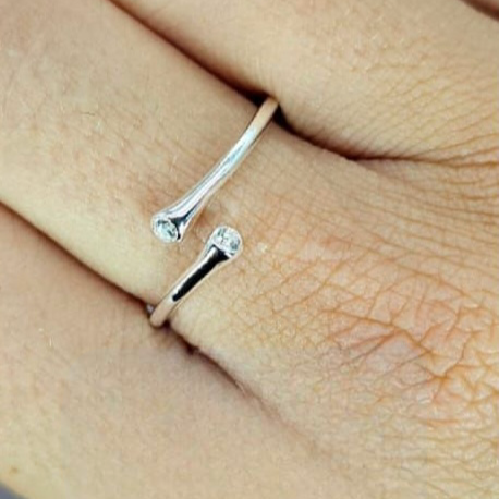 An open size fold over ring with cubic zirconia on each point, worn on a person's finger.