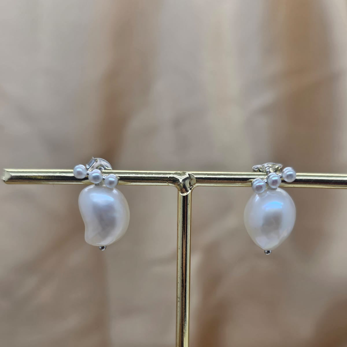 Pearl earrings on a gold stand with a blurred background