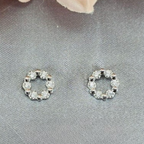 A pair of sterling silver circle studs with cubic zirconia detailing, displayed against a grey background.