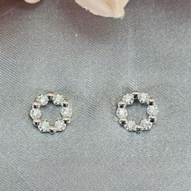 A pair of sterling silver circle studs with cubic zirconia detailing, displayed against a grey background.