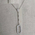 Silver necklace with a detailed pendant on a gray fabric background
