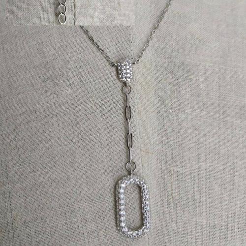Silver necklace with a detailed pendant on a gray fabric background