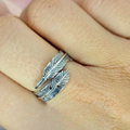 An adjustable sterling silver feather ring worn on a person's finger, showing the ring's detail and fit.