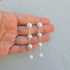 Pearl earrings held between fingers against a light background