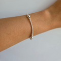 A sterling silver ball bracelet on an elastic band, worn on a person's wrist.