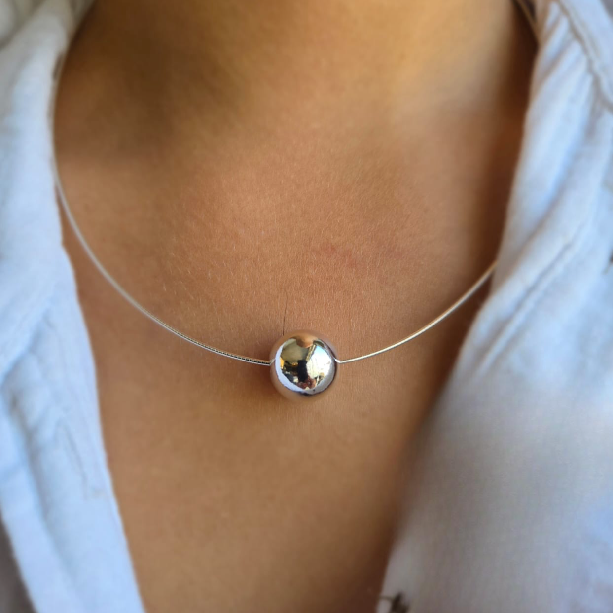 A silver choker necklace with a 14 mm ball slider, worn by a person with a white shirt.