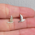 Silver bird-shaped earrings on a person's hand