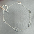 A sterling silver bracelet with Gucci links on a chain chain, displayed against a soft-focus background.