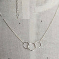 Silver necklace with interlocking rings on a textured gray background