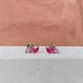 Pair of earrings with pink gemstones on a white surface