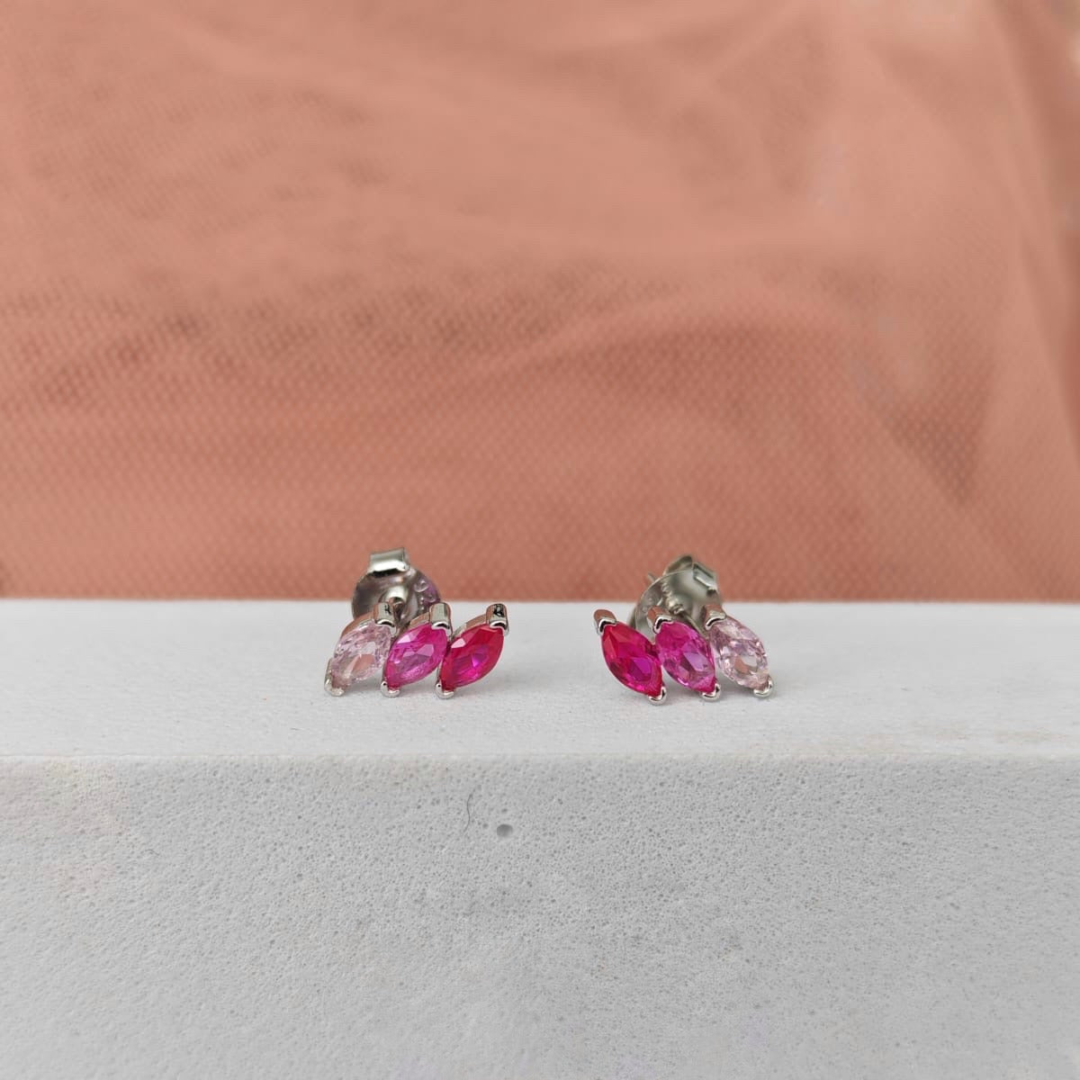 Pair of earrings with pink gemstones on a white surface