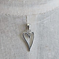 Silver heart-shaped pendant on a light fabric background