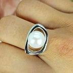 A sterling silver open-shaped ring with a freshwater pearl centered on the finger.