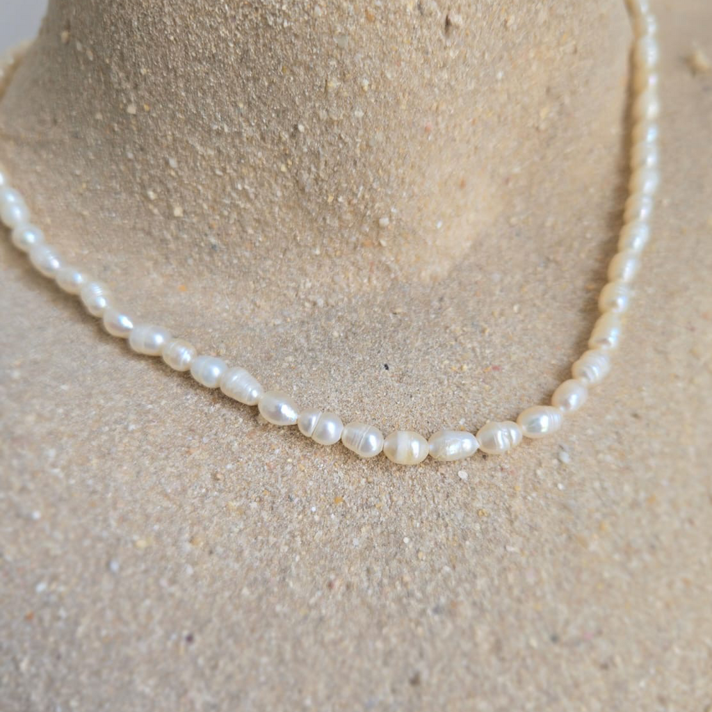 Pearl necklace on a mannequin bust with a neutral background