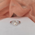 Silver ring with a pearl on a white surface with pink fabric in the background