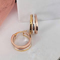 Rose gold hoop earrings on a light gray surface