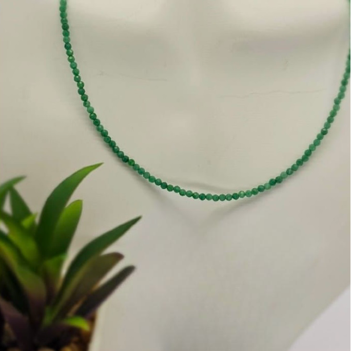A green jade semi precious necklace with a sterling silver clasp displayed on a mannequin bust.