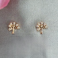 Gold tree-shaped earrings on a gray fabric background