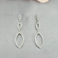 A pair of sterling silver drop earrings with cubic zirconia pavé, displayed against a light pink background.