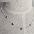 Silver necklace with small round pendants on a mannequin.